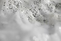 Kaboompics - Glossy White Cream Folds with Scattered Black Speckles, Skincare Texture Macro