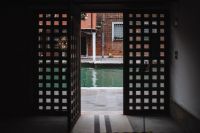 Kaboompics - Open Lattice Gate Framing a Canal View from a Shaded Murano Passage, Italy