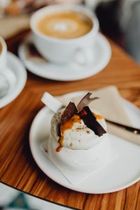 Kaboompics - Meringue Dessert with Chocolate Shards and Caramel Sauce beside Coffee
