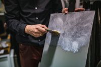 Kaboompics - Artist Brushing Gray Paint Across Canvas, Close-Up of a Textured Painting Process