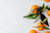 Kaboompics - Close-Up of Mandarin Oranges and Leaves on White Marble with Copy Space for Citrus Recipe Design