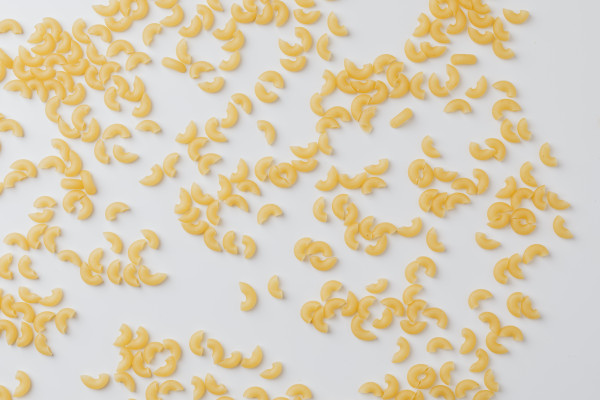 Elbow Macaroni Pasta Scattered Across White, Horizontal Food Styling ...