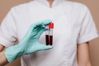 Kaboompics - Gloved Hands Holding Two Blood Sample Tubes on White Medical Uniform, Clinical Care Detail