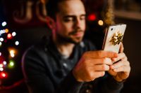 Kaboompics - Man Using Smartphone beside Wrapped Christmas Presents