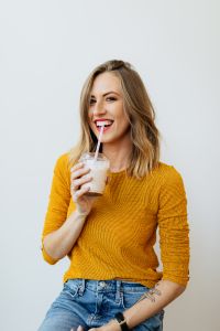 Kaboompics - Smiling Woman Sipping a Milkshake in a Yellow Sweater