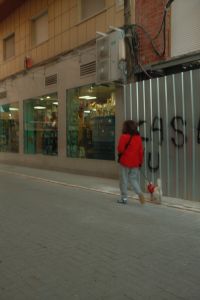 Kaboompics - Woman Walking a Small Dog Past Storefronts and Graffiti in a European Street