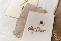 Kaboompics - Minimalist Handmade Greeting Card with Pressed Daisy on Textured Paper, Neutral Editorial Stationery Flat Lay