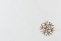 Kaboompics - Single Silver Snowflake Ornament on White Marble Background with Copy Space