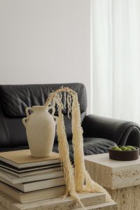 Kaboompics - Black Leather Sofa with Travertine Tables, Vase, Books and Green Apples