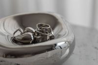 Kaboompics - Close-Up of Silver Rings in a Sculptural Chrome Bowl on Speckled Gray Stone, Jewelry Still Life