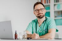 Kaboompics - Doctor Reviewing Notes Beside Open Laptop
