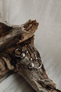 Kaboompics - Silver Ball Earrings on Driftwood with Neutral Copy Space