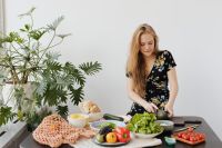 Kaboompics - Home Cook Preparing a Healthy Salad at a Table with Fresh Produce and Houseplant