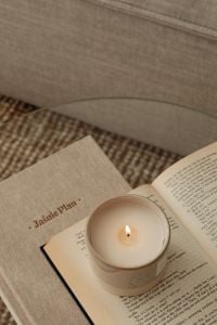 Kaboompics - Lit Candle on Open Book beside Textured Sofa