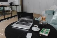 Kaboompics - Open Laptop and Coffee on Black Table in a Modern Living Room with Kitchen Background