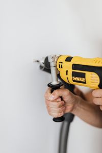 Kaboompics - Vertical Close-Up of a Man Drilling into a White Wall during Home Improvement