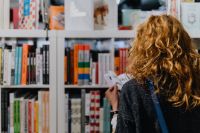 Kaboompics - Woman looking for a book in store