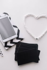 Kaboompics - Vertical Smartphone Still Life with Heart-Shaped Cable, Zigzag Notebook and Black Cards