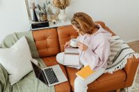 Kaboompics - Woman Working Beside Laptop with Notebook on Sofa