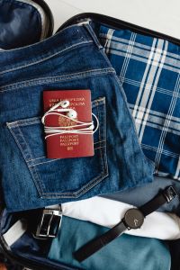 Kaboompics - Close-Up of Passport and Wired Earbuds on Jeans in a Packed Blue Suitcase
