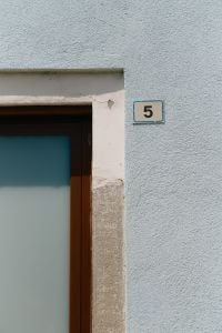 Kaboompics - House Number Five on Blue Plaster Wall with Wooden Door, Italy
