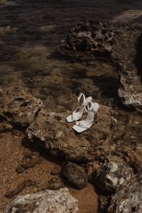 Kaboompics - White Strappy Heeled Sandals on a Rocky Shoreline