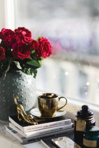 Gold cup of coffee and red roses bouqet