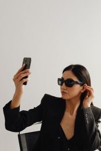 Kaboompics - Woman in Sunglasses Holding a Smartphone in a Black Suit