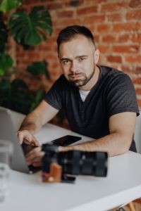 Kaboompics - Photographer Working on Laptop with Camera at Brick Wall Desk