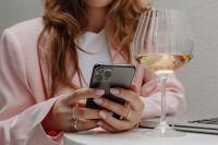 Kaboompics - Close-Up of Woman Holding a Smartphone and Wine Glass