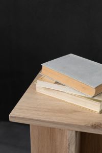 Kaboompics - Neutral Books on a Wooden Cube Side Table Against a Dark Interior Wall