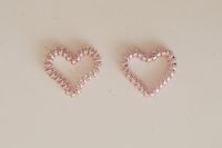 Kaboompics - Pair of Translucent Pink Beaded Heart Shapes on Speckled Beige Background