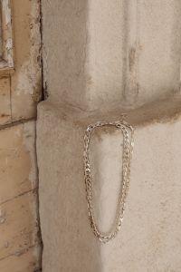 Kaboompics - Silver Chain Necklace Draped on a Textured Plaster Wall, Neutral Jewelry Product Photo