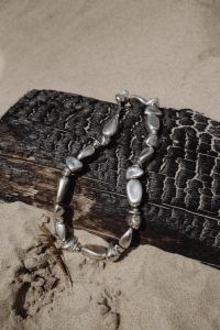 Kaboompics - Silver Metal Necklace on Driftwood in the Sand