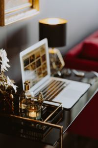 Kaboompics - Laptop Workspace with Candle, Perfume Bottles and Gold Decor