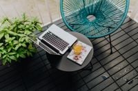 Kaboompics - A stylish garden chair and a small table on the balcony. Macbook laptop, book and a glass of orange juice.