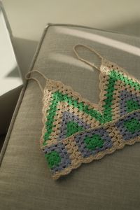Kaboompics - Vertical Close-Up of a Colorful Granny-Square Crochet Top on Neutral Upholstery