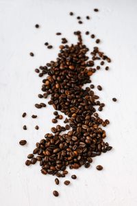 Kaboompics - Coffee Beans Scattered in a Vertical Trail on White for Menu and Recipe Layouts