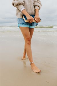 Kaboompics - Barefoot Woman Crossing Her Legs While Holding a Book on the Beach, Casual Summer Reading Scene