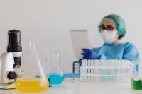 Kaboompics - Microscope and Laboratory Notebook With Scientist in Background