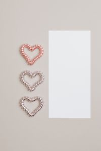 Kaboompics - Three Beaded Hearts Beside a Blank White Card on Beige Valentine Background