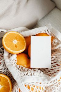 Kaboompics - Blank Business Card Mockup on an Orange-Filled Mesh Bag, Close-Up Citrus Branding
