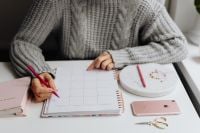 Kaboompics - Woman Planning the Month with Pink Calendar Desk Accessories