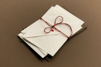 Kaboompics - Stack of White Envelopes Tied with Red String and Heart Seal