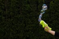 Kaboompics - Hand with Green Bubble Blaster Creating a Bubble Trail with Copy Space