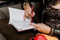 Kaboompics - A woman with a large ring and a golden watch writes down in the calendar