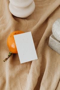 Kaboompics - Orange Fruit, Blank Branding Card and White Ceramic Vase with Stone Decor