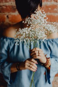 Kaboompics - A woman in a blue dress holds a branch of Baby's Breath flower