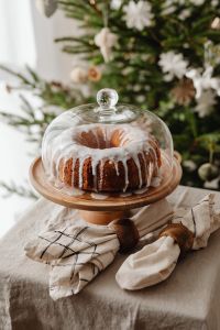 Kaboompics - Iced Bundt Cake under Glass Cake Dome beside Christmas Tree