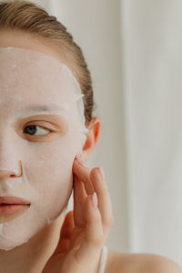 Kaboompics - Woman Gently Pressing a White Sheet Mask onto Her Face